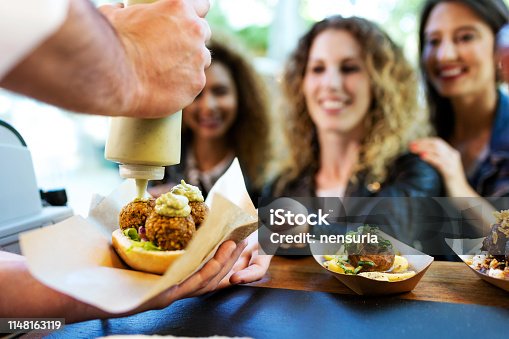 istock Three beautiful young women buying meatballs on a food truck. 1148163119