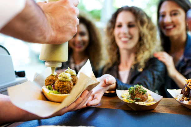 trzy piękne młode kobiety kupujące klopsiki na food trucku. - people behavior smiling mode of transport zdjęcia i obrazy z banku zdjęć