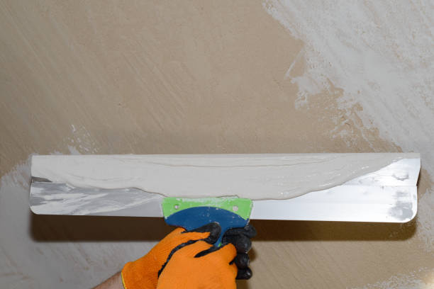 istock hand with a long trowel with white putty on a plaster background 1148165476