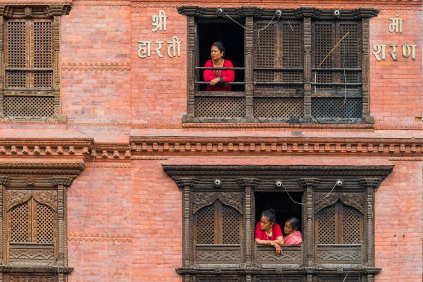 dans la journée dans la région de swayambhunath. les gens népalais qui vivent sur le vieux bâtiment de cru là se tiennent aux fenêtres pour observer beaucoup de touristes magasinez au premier étage. - swayambhunath photos et images de collection