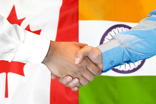 Business handshake on the background of two flags. Men handshake on the background of the India and Canada flag. Support concept