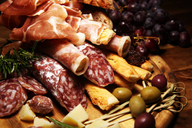 istock antipasto various appetizer. Cutting board with prosciutto, salami, cheese, bread and olives on dark wooden background 1148171600