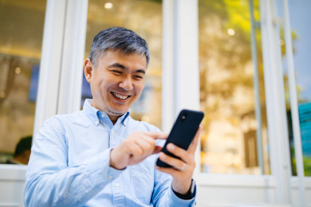 istock Asian Ethnicity businessman using mobile phone, business or communication technology concept, lens flare effect. 1148171770
