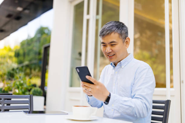 istock Asian Ethnicity businessman using mobile phone, business or communication technology concept, lens flare effect. 1148171775
