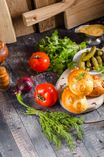 pies, loaf bread, dough on a wooden vintage cutting board old rustic, mustard sauce-dish, tomato, greens, black pepper gherkins, cucumbers, on the table top, side, bottom shot angle, fork and knife pasteles, pan, masa en una tabla de corte vintage de madera antigua rústica, salsa de mostaza-plato, tomate, verduras, pepinillos de pimienta negra, pepinos, en la parte superior de la mesa, lado, ángulo de disparo inferior, tenedor y cuchillo