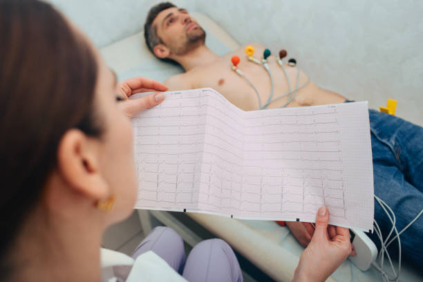patient getting heart rate monitored at hospital. Close-up Of Ecg Report patient getting heart rate monitored with electrocardiogram equipment. cardiogram test, Close-up Of Ecg Report electrode stock pictures, royalty-free photos & images