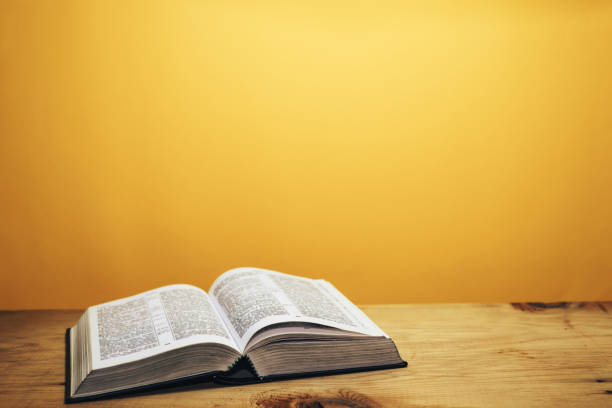istock Bible on a brown wooden table. Beutiful orange wall background. 1148178558