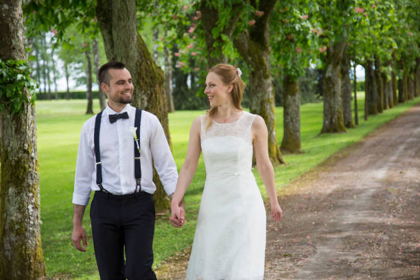 istock Bride and groom walking through treelined path 1148180326