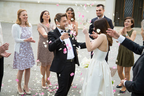 istock Guests throwing rose petals on bride and groom 1148180328
