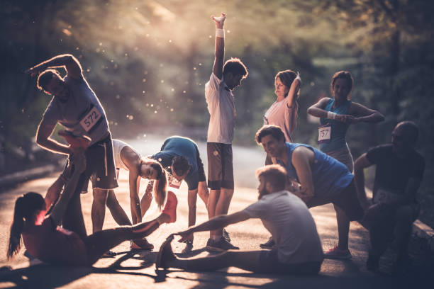 grand groupe de coureurs se réchauffant sur une route au coucher du soleil avant le marathon. - échauffement photos et images de collection