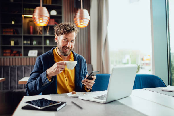 istock Businessman drinking coffee and using smart phone in cafe. 1148182263