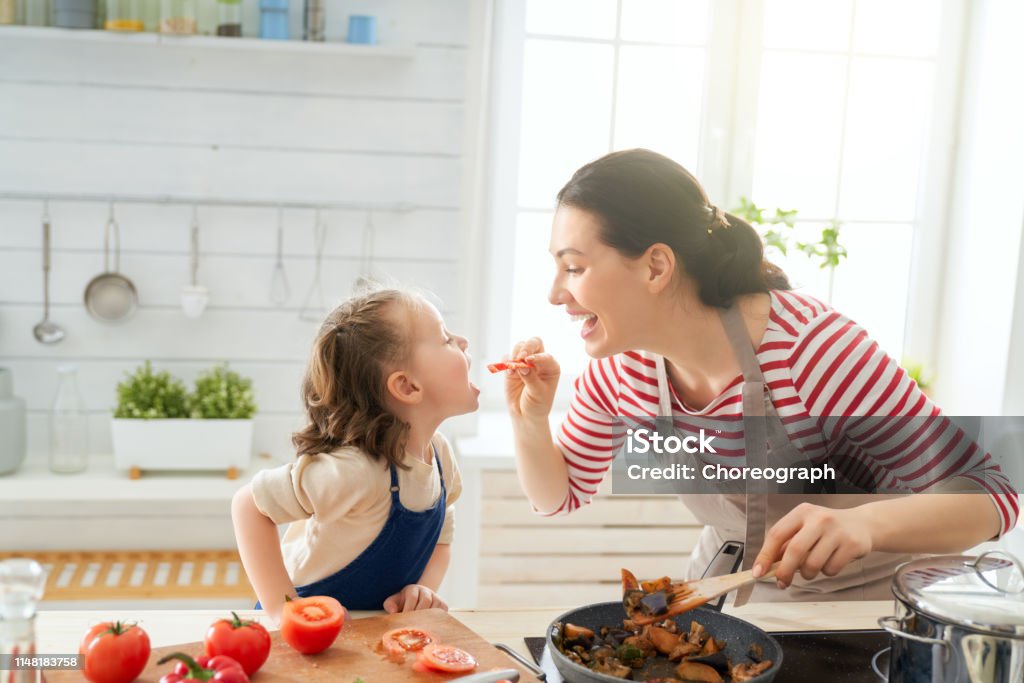 Happy family in the kitchen. Healthy food at home. Happy family in the kitchen. Mother and child daughter are preparing proper meal. Cooking Stock Photo