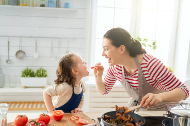 Happy family in the kitchen. Healthy food at home. Happy family in the kitchen. Mother and child daughter are preparing proper meal. family with one child stock pictures, royalty-free photos & images