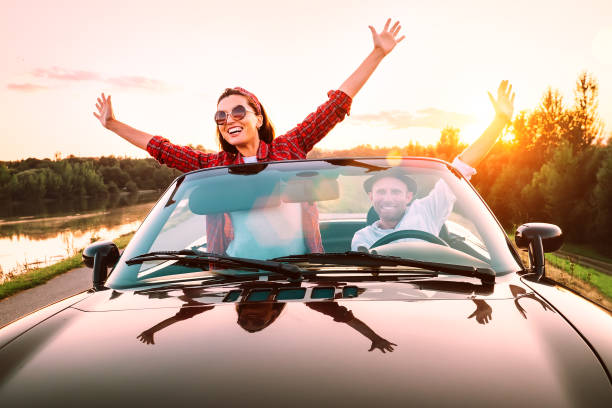 viaggiare in auto - coppia felice innamorata andare in auto cabriolet in orario tramonto - car men sensuality couple foto e immagini stock