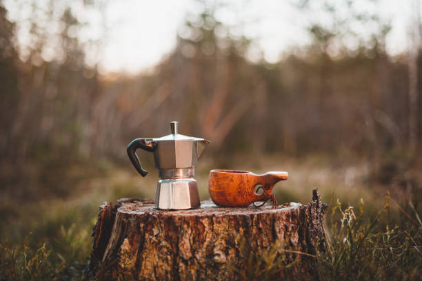 Coffee maker and wooden kuksa stand on a stump in the forest. Coffee maker and cup in focus. The forest background is blurred. Coffee maker and wooden kuksa stand on a stump in the forest. Coffee maker and cup in focus. The forest background is blurred. norrbotten province stock pictures, royalty-free photos & images