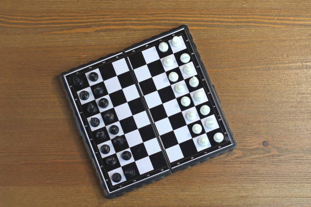 istock Foldable plastic chessboard with black and white chess on a wooden surface. Top view 1148186376