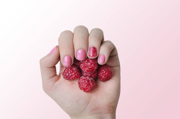 istock Female hand with pink nail design holding raspberry 1148193961