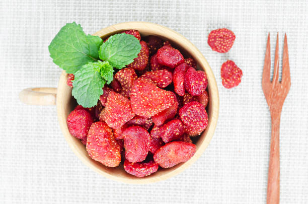 Dried Strawberries in white cup on tablecloth background.