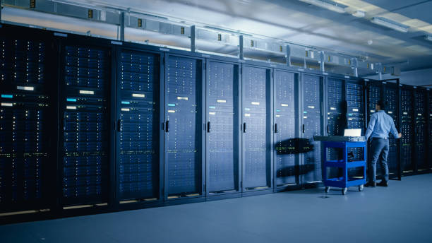 istock In the Modern Data Center: IT Engineer Doing Maintenance and Diagnostics. Pushes Cart alongside Server Racks, Opens Cabinet to Install New Hardware for Planned System Update, Equipment Replacement. 1148195900