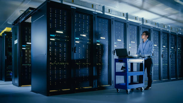 istock In the Modern Data Center: IT Engineer Doing Maintenance and Diagnostics. Pushes Cart alongside Server Racks, Ready to Install New Hardware for Planned System Update, Equipment Replacement. 1148195962