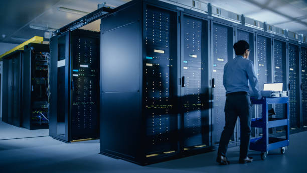 istock In the Modern Data Center: IT Engineer Doing Maintenance and Diagnostics. Pushes Cart alongside Server Racks. Planned System Equipment Update and Maintanence. 1148195970