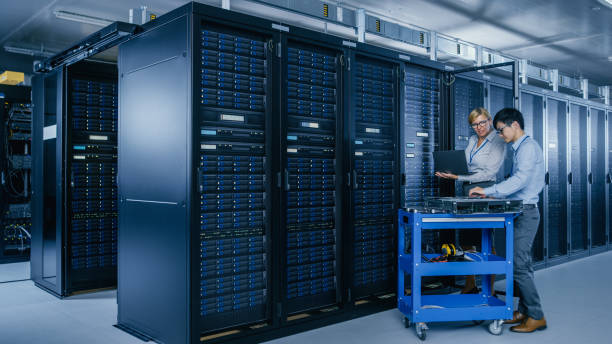 istock In the Modern Data Center: Engineer and IT Specialist Work with Server Racks, on a Pushcart Equipment for Installing New Hardware. Specialists Doing Maintenance and Diagnostics of the Database. 1148195999