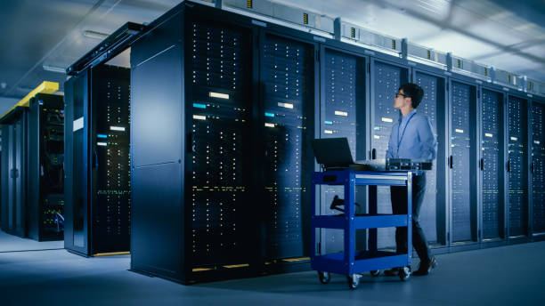istock In the Modern Data Center: IT Engineer Doing Maintenance and Diagnostics. Pushes Cart alongside Server Racks, Ready to Install New Hardware for Planned System Update, Equipment Replacement. 1148196003