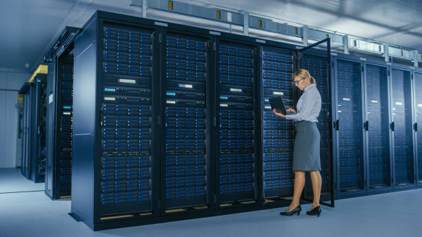 istock In Data Center: Female IT Technician Stand Near Opened Rack Cabinet and Runs Maintenance Program on Laptop, Controls Operational Server's Optimal Functioning. 1148196049