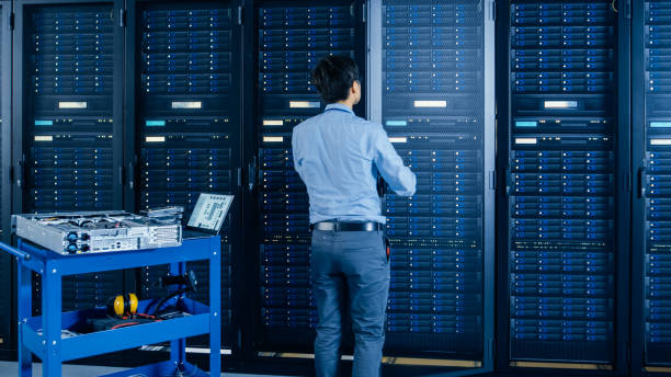 istock In the Modern Data Center: IT Engineer Doing Maintenance and Diagnostics. Works with Opened Cabinet and Installs New Hardware for Planned System Update, Replacement. Cart Stand alongside Server Racks. 1148196923