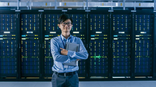 istock In the Modern Data Center: Portrait of IT Engineer Standing with Server Racks Behind Him, Holding Laptop after Finishing Doing Maintenance and Diagnostics Procedure. 1148197000