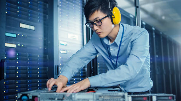istock In the Modern Data Center: IT Engineer Wearing Protective Headphones Installs New Hardware for Server Rack. IT Specialist Doing Maintenance, Running Diagnostics and Updating Hardware. 1148197035