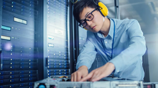 istock In the Modern Data Center: IT Engineer Wearing Protective Headphones Installs New Hardware for Server Rack. IT Specialist Doing Maintenance, Running Diagnostics and Updating Hardware. 1148197045