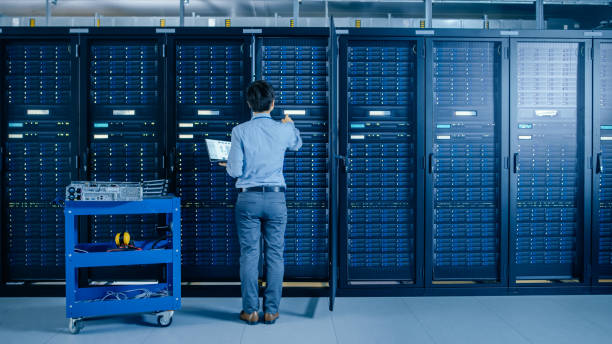 istock In the Modern Data Center: IT Engineer Doing Maintenance and Diagnostics. Works with Opened Cabinet and Installs New Hardware for Planned System Update, Replacement. Cart Stand alongside Server Racks. 1148197101