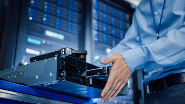 istock In the Modern Data Center: IT Engineer Installs New HDD Hard Drive and Other Hardware into Server Rack Equipment. IT Specialist Doing Maintenance, Running Diagnostics and Updating Hardware. 1148197221