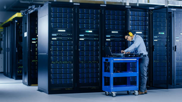 istock In Data Center: IT Engineer Wearing Protective Muffs Installs New Hardware for Server Rack. Specialist Doing Maintenance, Running Diagnostics and Updating Hardware for Stable Functioning of a System. 1148197230