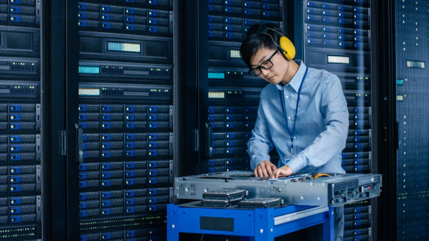 in data center: it engineer wearing protective muffs installs new hardware for server rack. specialist doing maintenance, running diagnostics and updating hardware for stable functioning of a system. - network server rack computer mainframe imagens e fotografias de stock