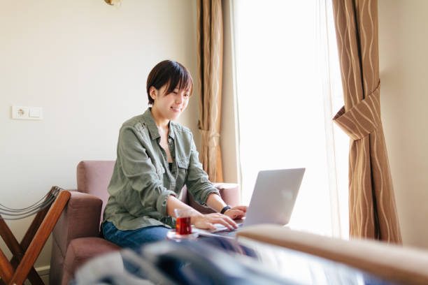 istock Young woman working on laptop in hotel room 1148201155