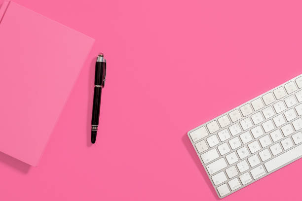 istock PInk notebook, black pen and computer keyboard on a pink background. 1148204272