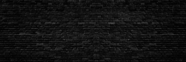 Wide old black shabby brick wall texture. Dark masonry panorama. Brickwork panoramic grunge background