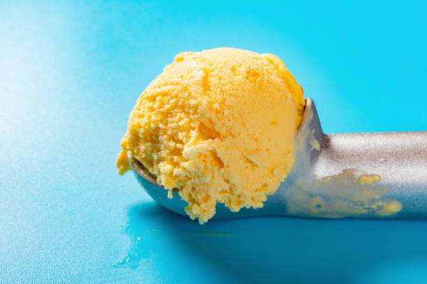 istock spoon with mango flavor ice cream ball on blue background close up 1148205158