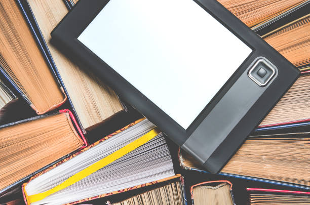 istock The e-book with a white screen lies on the open multi-colored books that lie on a dark background, close-up 1148206880