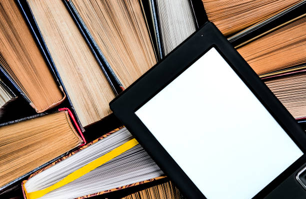 istock The e-book with a white screen lies on the open multi-colored books that lie on a dark background, close-up 1148206894