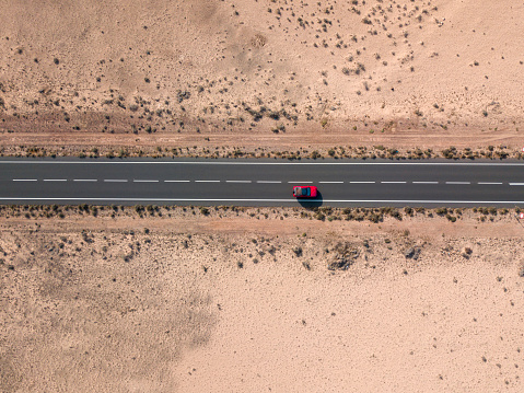 Aerial view of a red car in the desert valleys of the island of Lanzarote, Canary Islands, Spain. Paths and roads. Africa