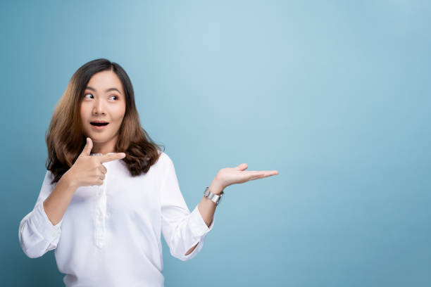 istock Woman pointing to copy space isolated over blue background 1148208580