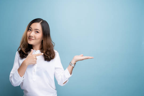 istock Woman pointing to copy space isolated over blue background 1148208601