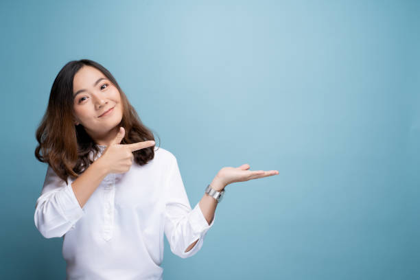 Woman pointing to copy space isolated over blue background