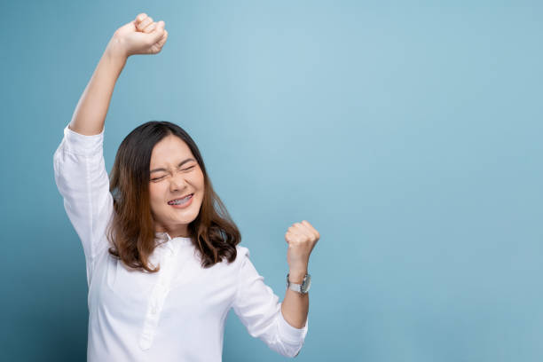 istock Happy woman make winning gesture isolated over blue background 1148208709