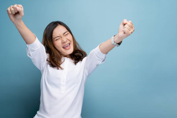 istock Happy woman make winning gesture isolated over blue background 1148208819