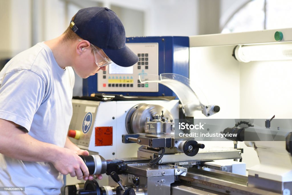 Junge Auszubildende in der Berufsausbildung an einer Drehmaschine in der Branche - Lizenzfrei Berufliche Beschäftigung Stock-Foto