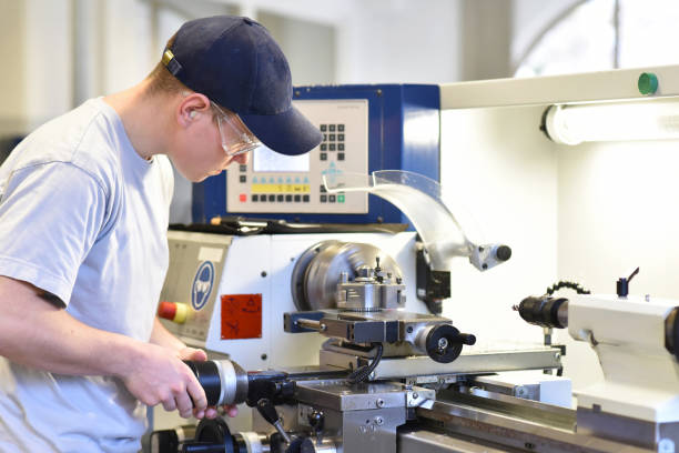 joven aprendiz en la formación profesional que trabaja en una máquina de torneado en la industria - machine tool fotografías e imágenes de stock